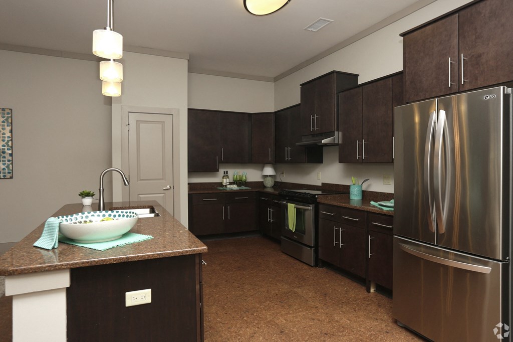 a large kitchen with stainless steel appliances and dark wood cabinets
