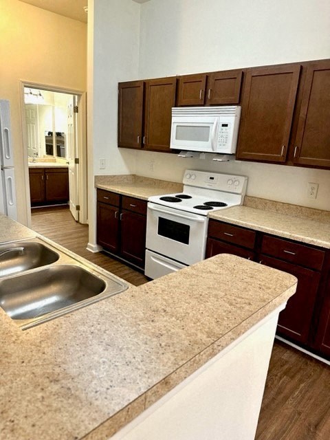 A kitchen with a white stove top oven and a white microwave above the stove.