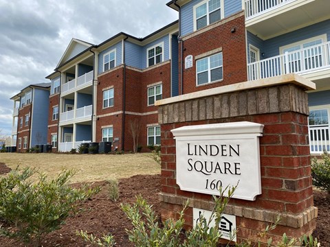 Exterior of Linden Square Apartments, with a sign in front of the building.
