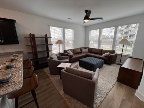 A living room with a brown couch and a dining table.