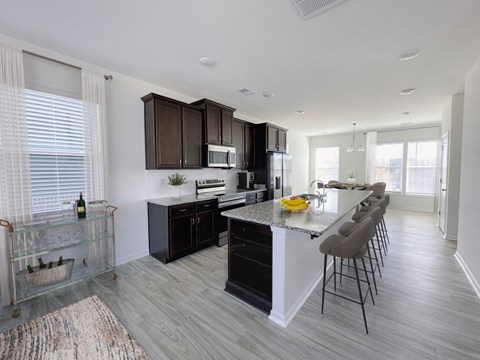 A modern kitchen with dark brown cabinets and a white island.