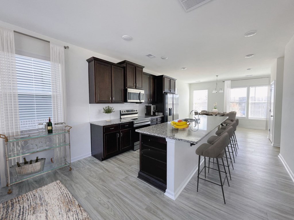 A modern kitchen with dark brown cabinets and a white island.