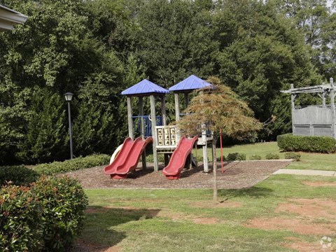 A playground with a red slide and a blue canopy.