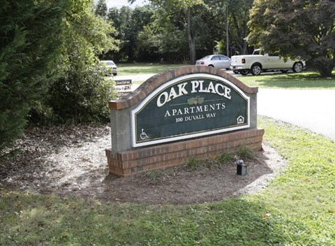 a sign for oak place apartments on the side of a road
