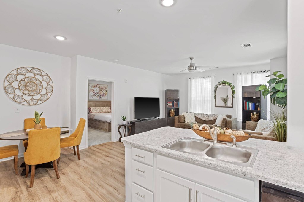 Ovata at Reedy Creek kitchen and connected living room with modern appliances, a peninsula, white cabinetry and LVT flooring.