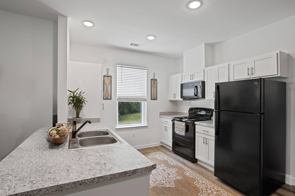 Ovata at Reedy Creek kitchen with modern appliances, a peninsula, white cabinetry and LVT flooring.