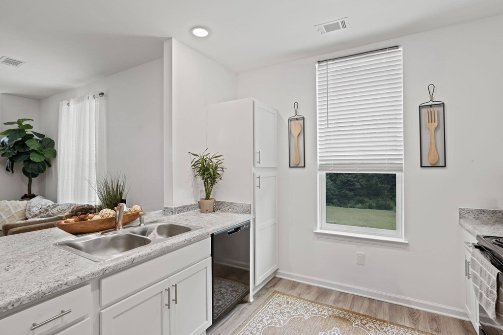 A kitchen with a white sink and a window with blinds.