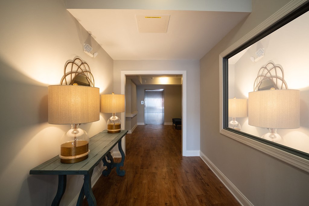 A hallway with a bench and two lamps on the wall.
