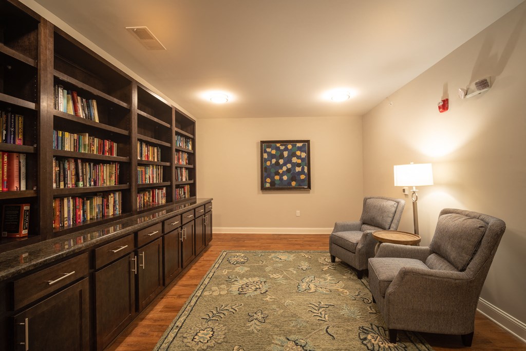 A room with a bookshelf filled with books and two chairs.