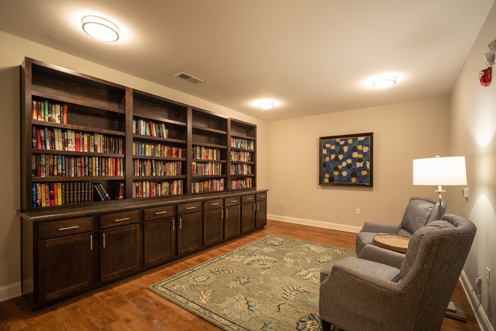 A room with a bookshelf, a chair, and a painting on the wall.