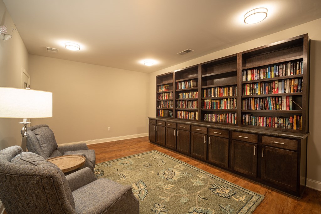 A room with a bookshelf filled with books and a grey armchair.