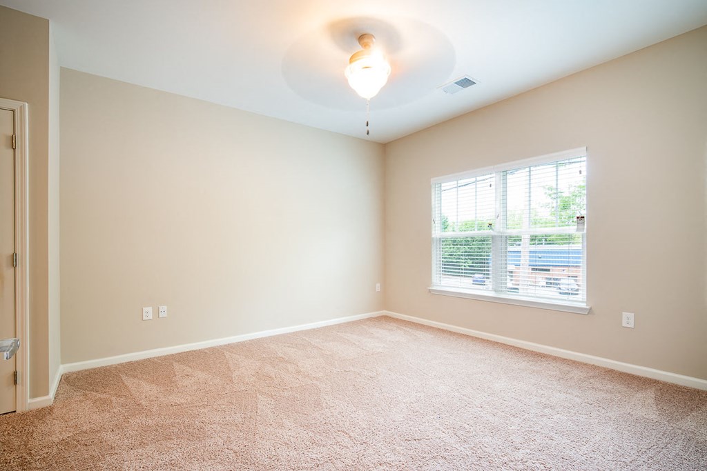 A room with a carpeted floor and a window.
