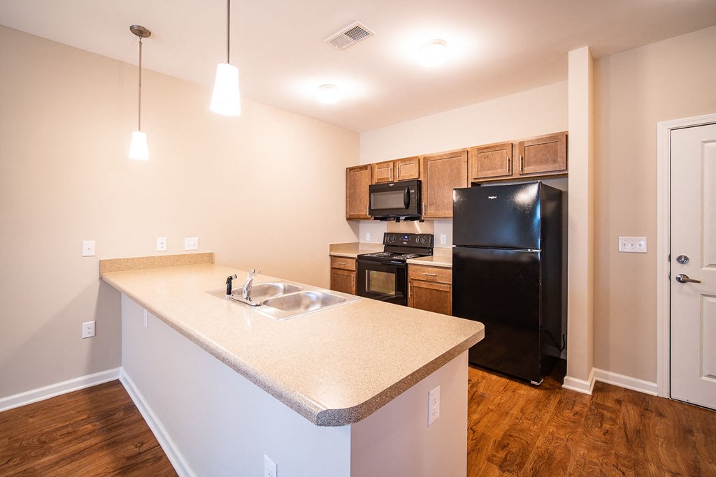A kitchen with a black refrigerator and wooden cabinets.