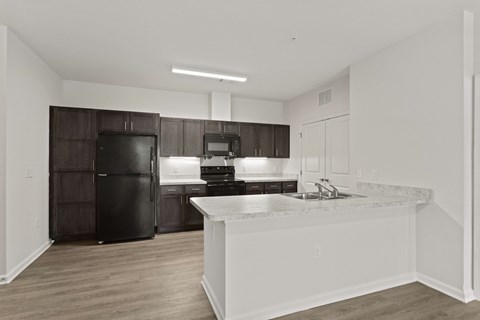 A kitchen with a black refrigerator and white countertops.