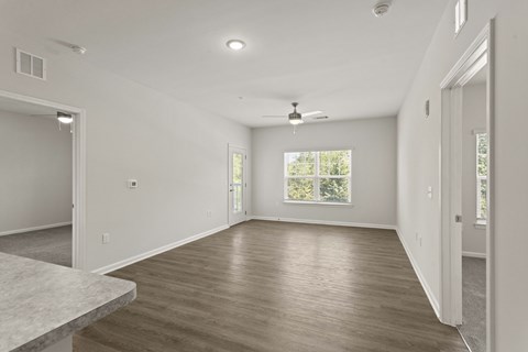 A spacious room with wooden flooring and a ceiling fan.