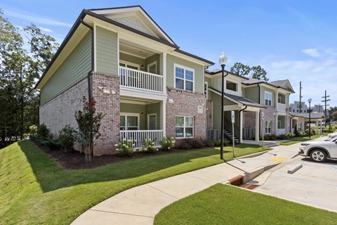 A two-story apartment building with a green roof and white balcony railings.