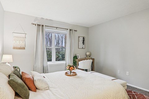 A bedroom with a large bed and a window with curtains.