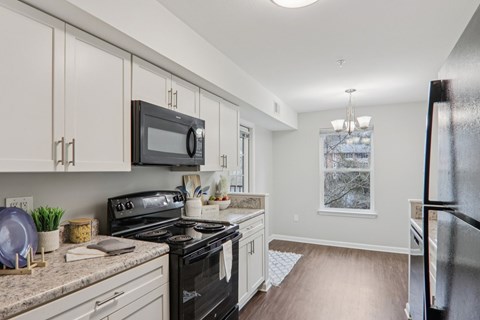 A kitchen with a black stove top oven and white cabinets.