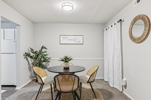 Plantations at Haywood living room with table, beige carpet, chairs, and attached kitchen with white appliances