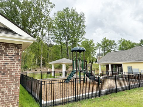 A playground with a green slide and a white gazebo.