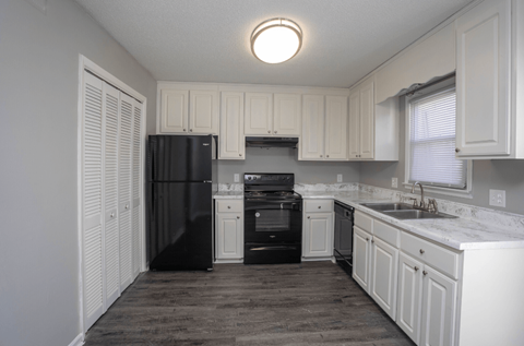 A kitchen with black appliances and white cabinets.