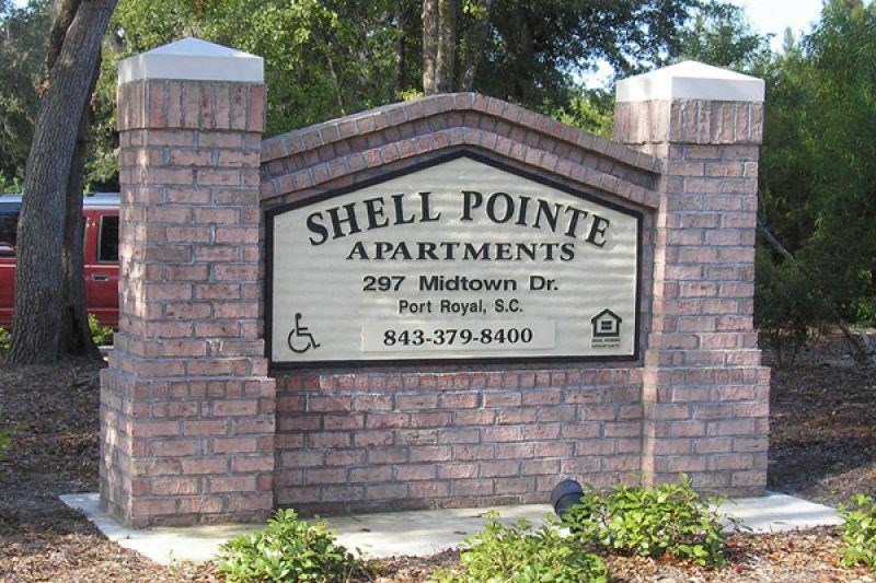 a sign for shell pointe apartments in front of a brick wall