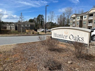 A sign for Hunter Oaks Apartment Homes in front of some buildings.
