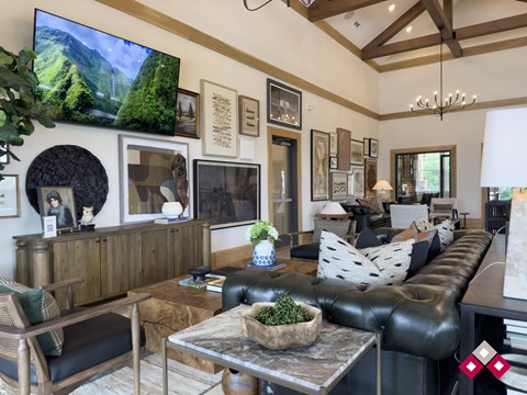 A living room with a large leather couch and a flat screen TV mounted on the wall.