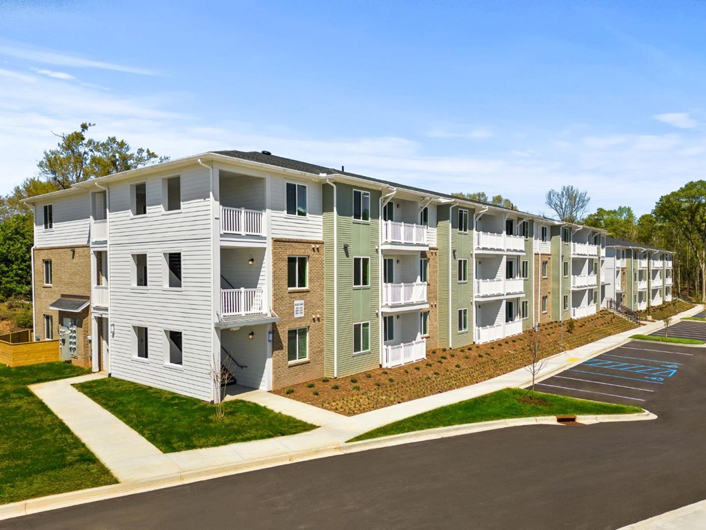 One Bedroom Apartments in Greenville SC - Alston - Exterior of One of the Property Buildings with Three Levels and Private Balconies, with a Parking Lot in Front
