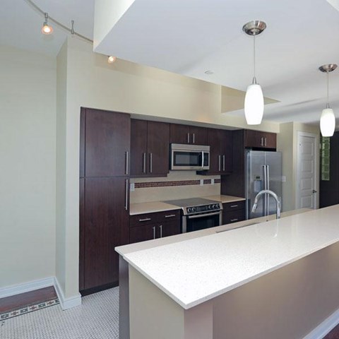 A kitchen with dark wood cabinets and white countertops.