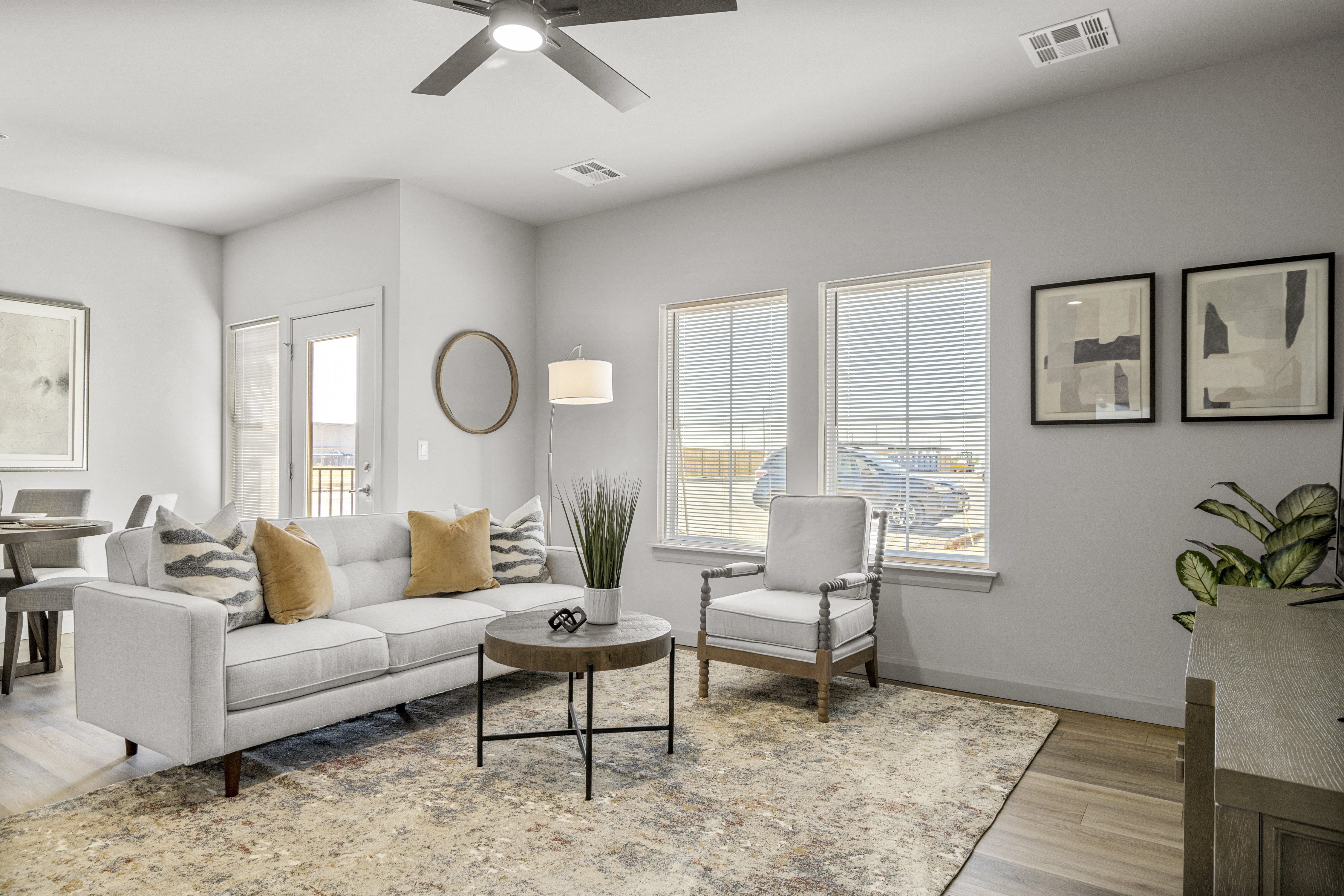 A living room with a white couch, a coffee table, and a ceiling fan.