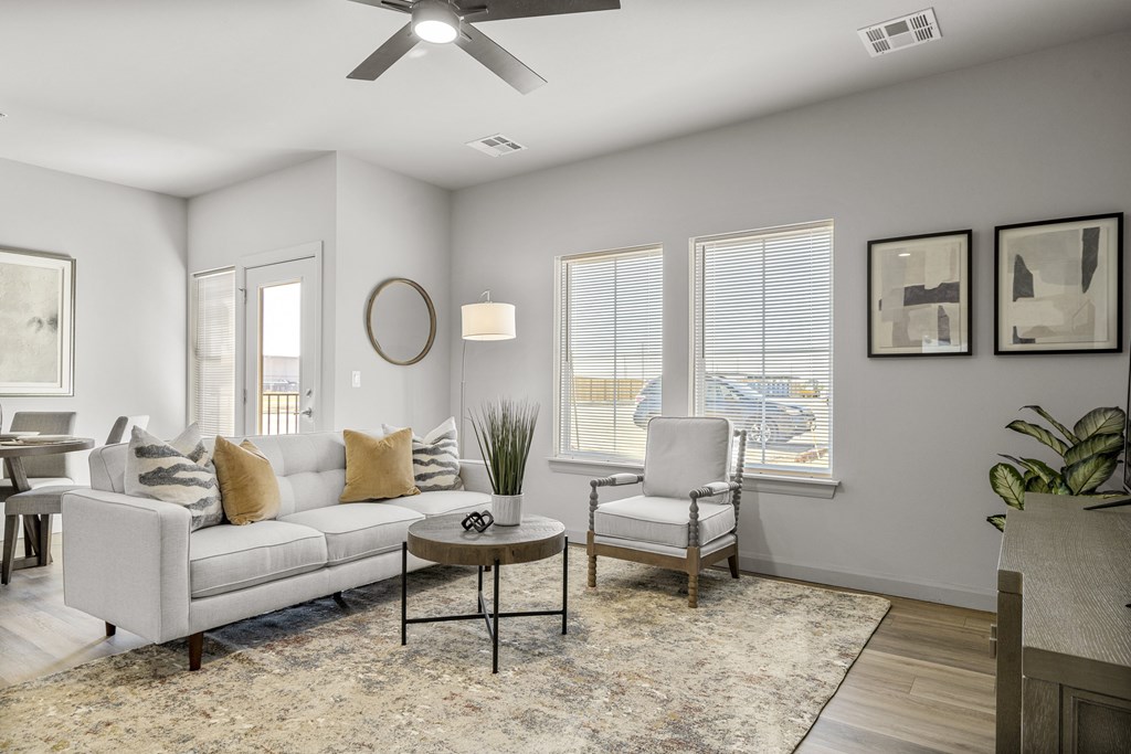 A living room with a white couch, a coffee table, and a ceiling fan.