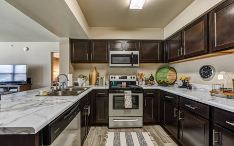 A modern kitchen with dark wood cabinets and stainless steel appliances.