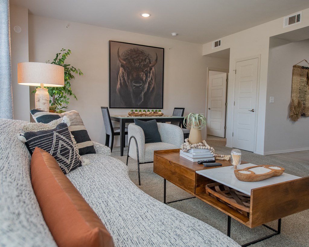 A living room with a grey couch and a painting of a bull on the wall.