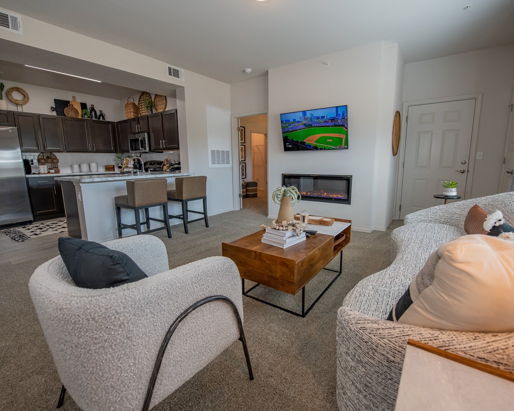 A living room with a grey couch, a wooden coffee table, and a television displaying a baseball game.