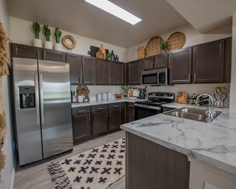 A kitchen with a refrigerator, microwave, and sink.