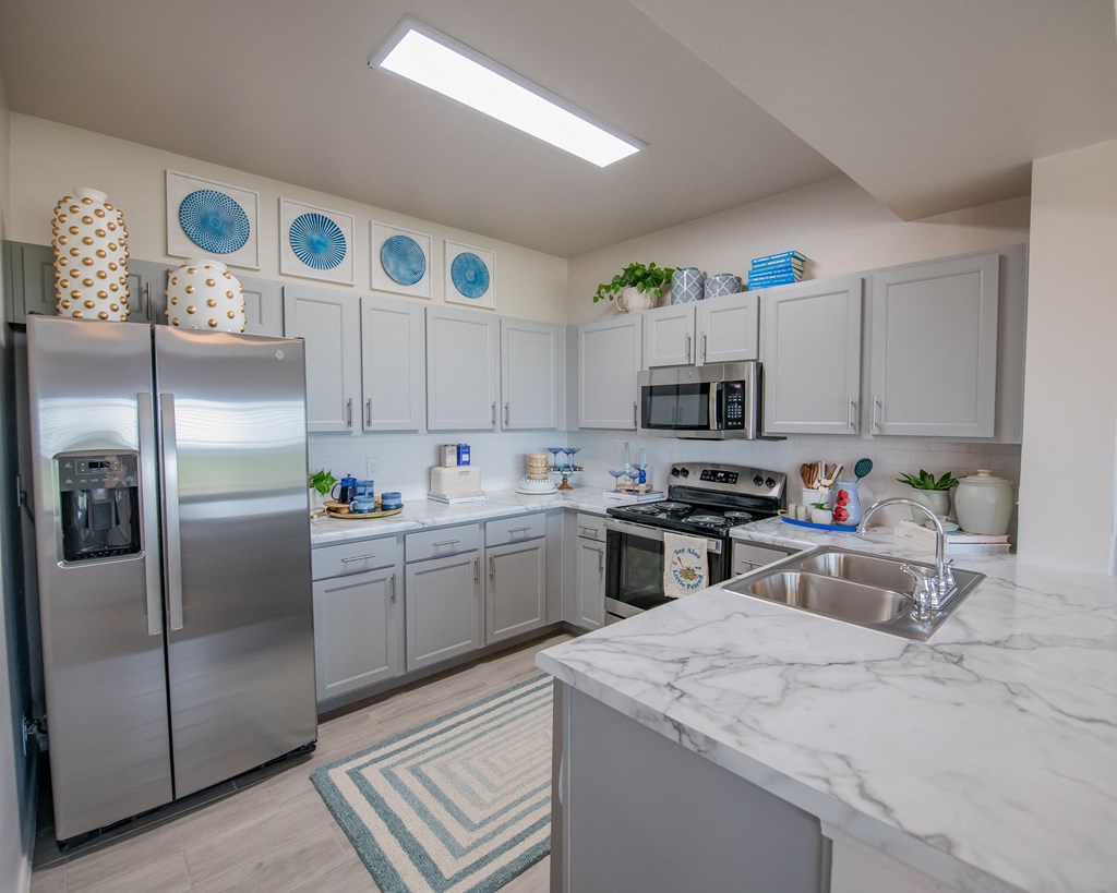 A kitchen with a refrigerator, microwave, oven, and sink.