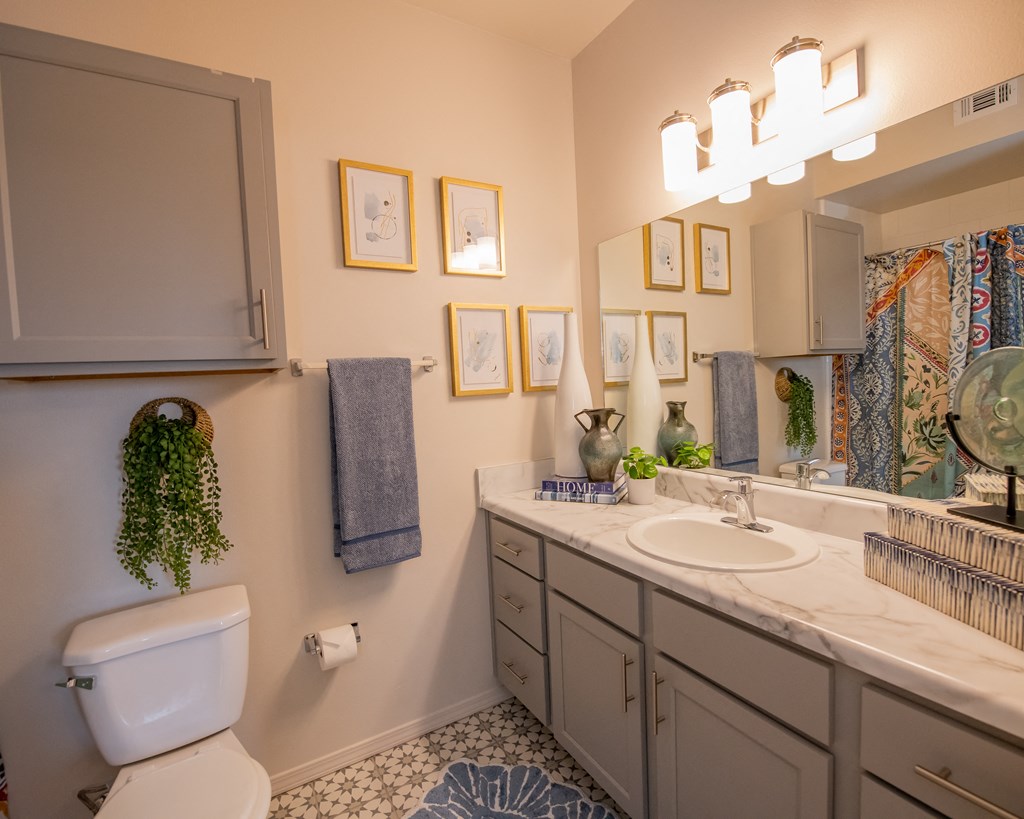 A bathroom with a white toilet, a sink, and a mirror.