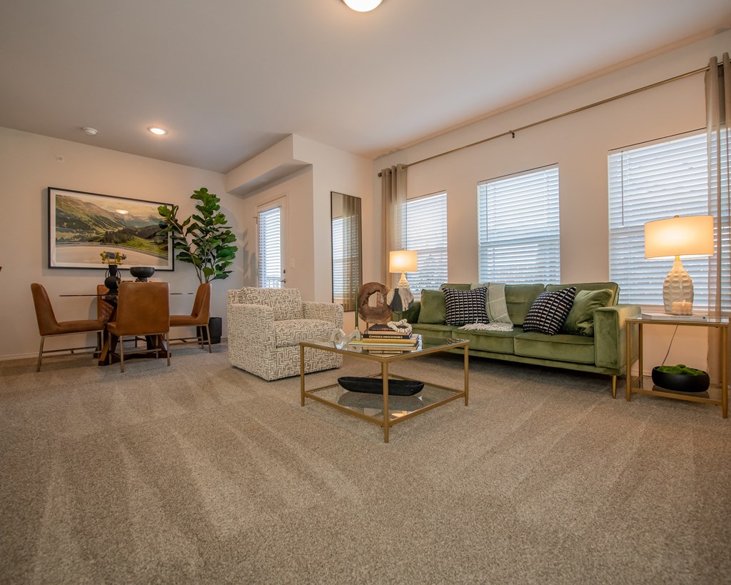 A living room with a green couch, a coffee table, and a painting on the wall.