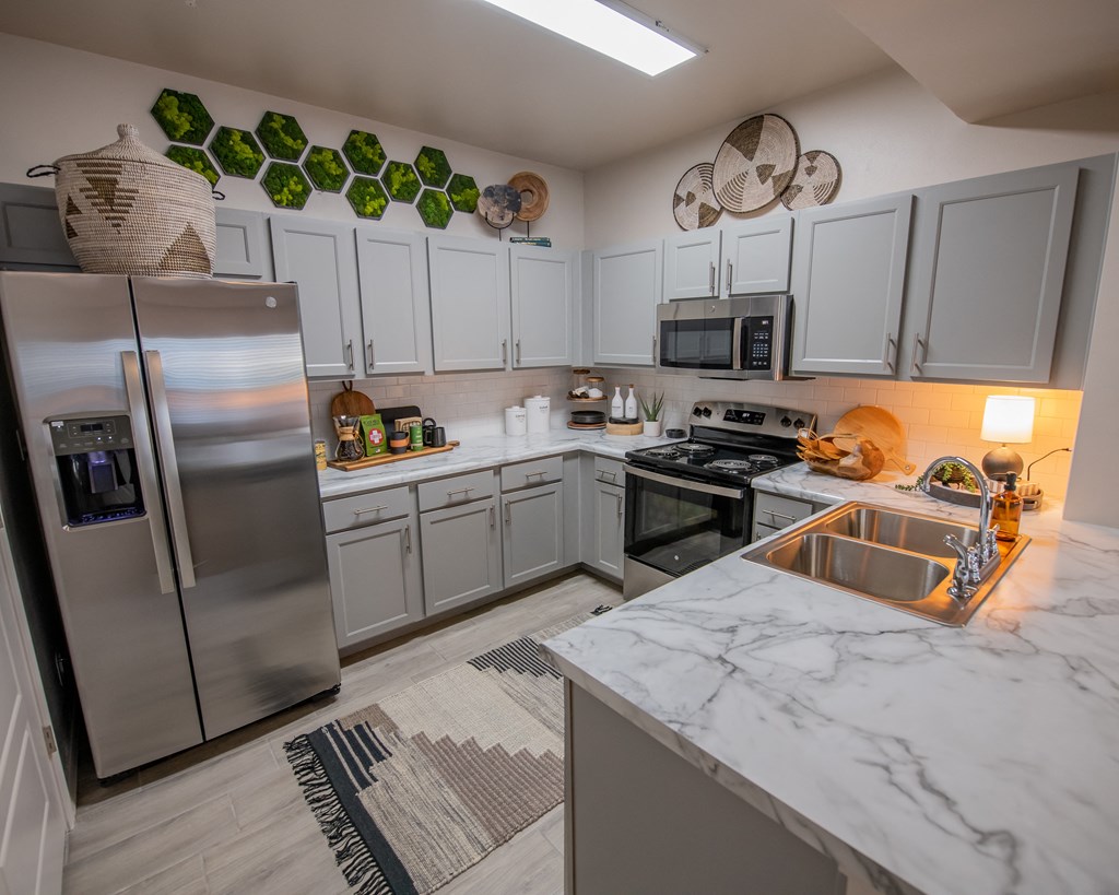 A modern kitchen with a marble countertop and stainless steel appliances.