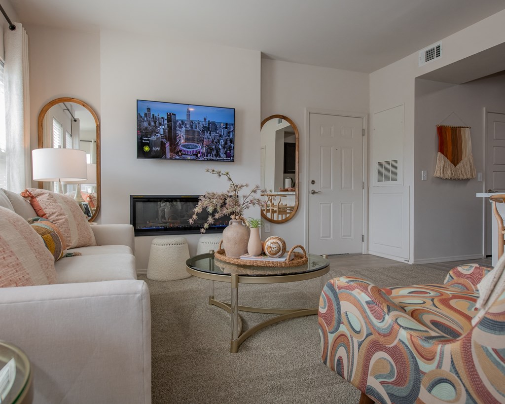 A living room with a white couch, a coffee table, and a flat-screen TV mounted on the wall.