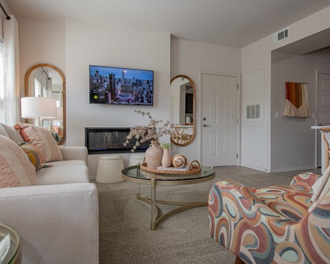 A living room with a white couch, a coffee table, and a flat-screen TV mounted on the wall.