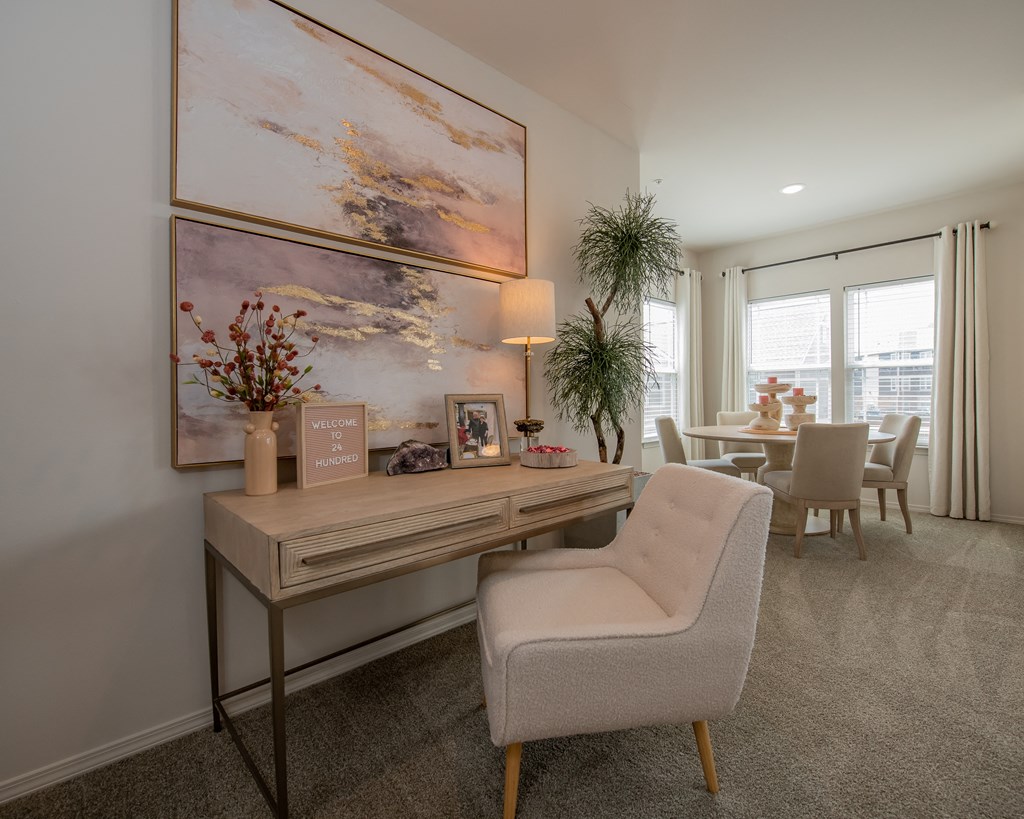A room with a desk and a chair in front of a large painting.