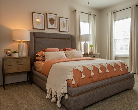 A bedroom with a large bed and a nightstand with a lamp.