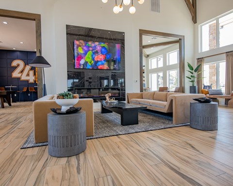 A modern living room with a large TV and wooden floors.