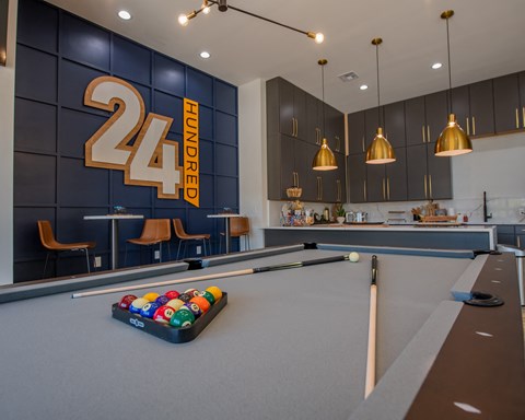 A pool table with a 24 Hundred sign in the background.