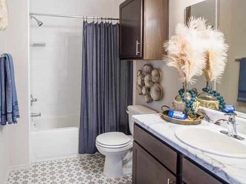 A bathroom with a white toilet, a white sink, and a shower with a grey curtain.