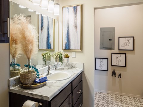 A bathroom with a marble counter top and a large mirror.