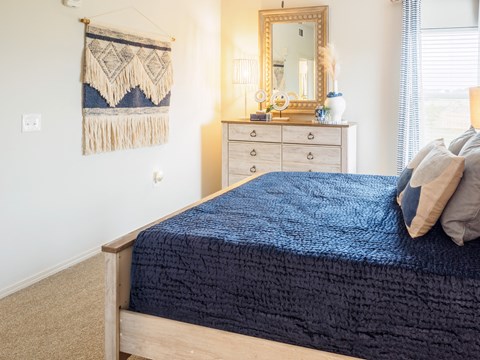 A bedroom with a bed, dresser, and mirror.