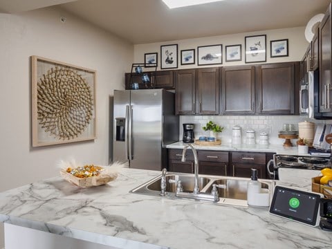 A kitchen with a marble countertop and a fridge.